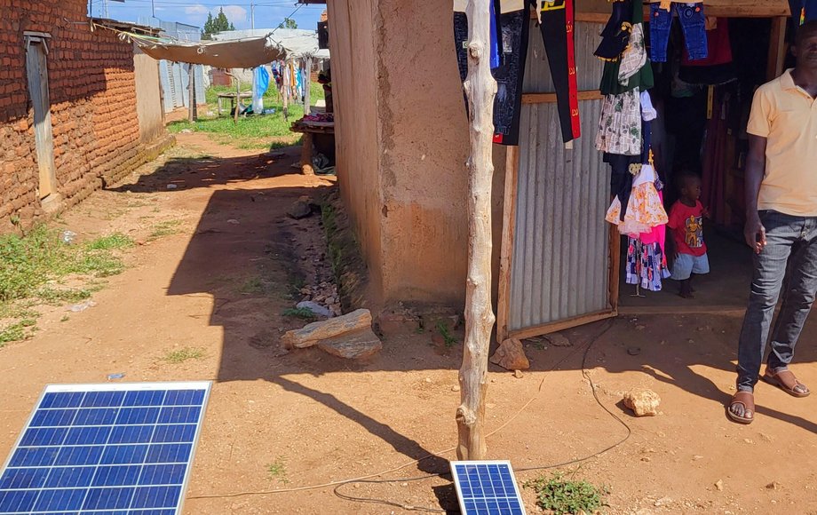 Lehmhütte in Afrika, vor dem Solarmodule liegen