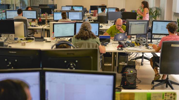 An open-plan office with lots of people and even more computer monitors.