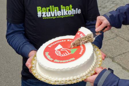 Eine Torte wird angeschnitten. Auf der Torte die Aufschrift: «Öffentliche Hand und Bürgerhand – Berliner Stromnetz»