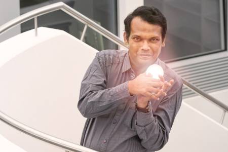 Ein Mann auf einer Treppe hält einen Spiegel mit Lichtreflexen in der Hand.