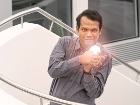 Ein Mann auf einer Treppe hält einen Spiegel mit Lichtreflexen in der Hand.