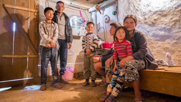 Stolz präsentiert sich eine Familie mit vier Kindern vor einer Wasseraufbereitungsanlage in ihrer einfachen Behausung.