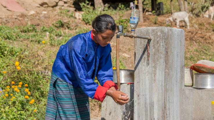 An einer betonierten Wasserstelle wäscht ein Mädchen seine Hände.