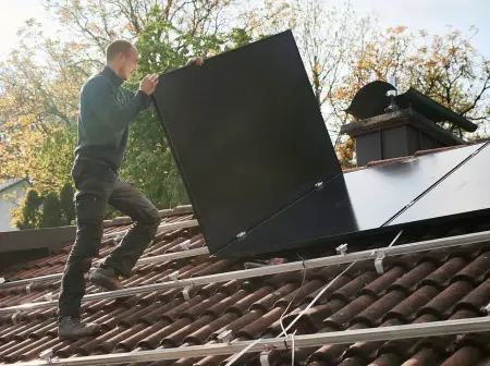 Ein junger Mann ist dabei, ein weiteres Modul in eine PV-Dachanlage zu integrieren.