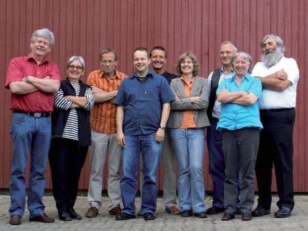 Gruppenbild: Mitbegründer der EWS stehen mit verschränkten Armen vor einer Holzwand.