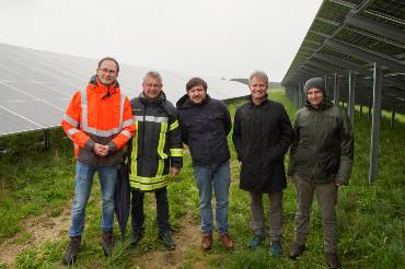 Fünf Männer stehen nebeneinander zwischen Photovoltaikmodulen