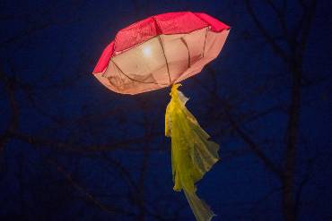 Erleuchtete Lampenkonstruktion aus Regenschirmen vor dunklem Nachthimmel