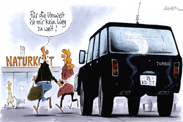Cartoon von Maester: Ein Mann und eine Frau gehen aus ihrem SUV in einen Biosupermarkt, er sagt "Für die Umwelt ist mir kein Weg zu weit"