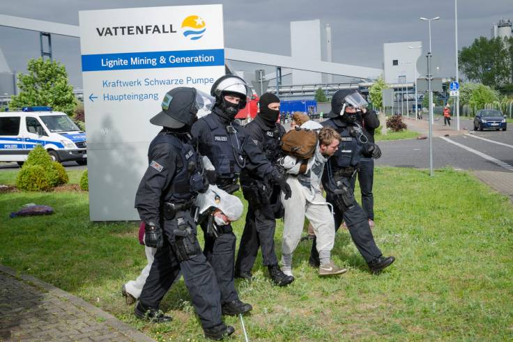 Vor dem Wegschild des Vattenfall-Kraftwerks «Schwarze Pumpe» nehmen vier vermummte Polizisten zwei Aktivisten in den Klammergriff und führen sie ab.