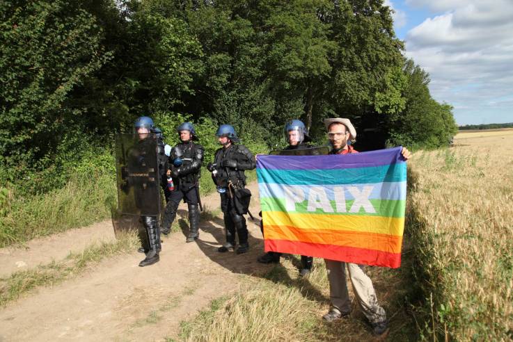 Ein Aktivist mit Friedensfahne neben Polizisten