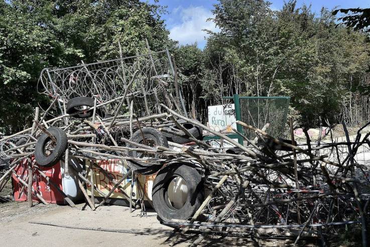 Wegsperre aus Absperrgittern, Holzstangen, Autoreifen und Stacheldraht