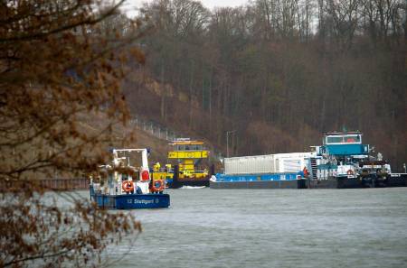 Zwei Schiffe im Verbund an einer Flussbiegung; im Vordergrund ein Boot der Wasserpolizei