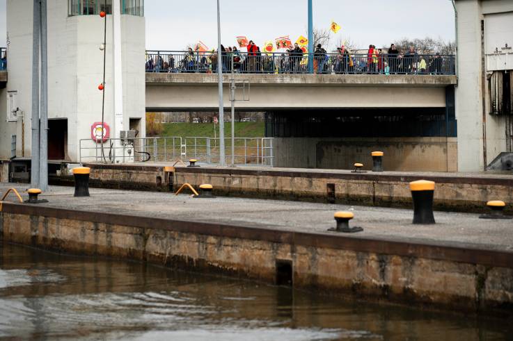 Eine Schleuse, dahinter eine Brücke, über die ein Demonstrationszug zieht.