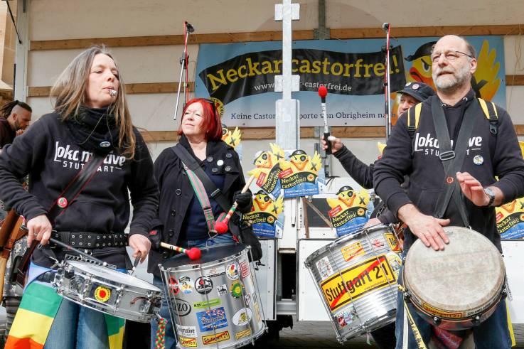 Protestierende rühren vor einer Bühne ihre Trommeln.