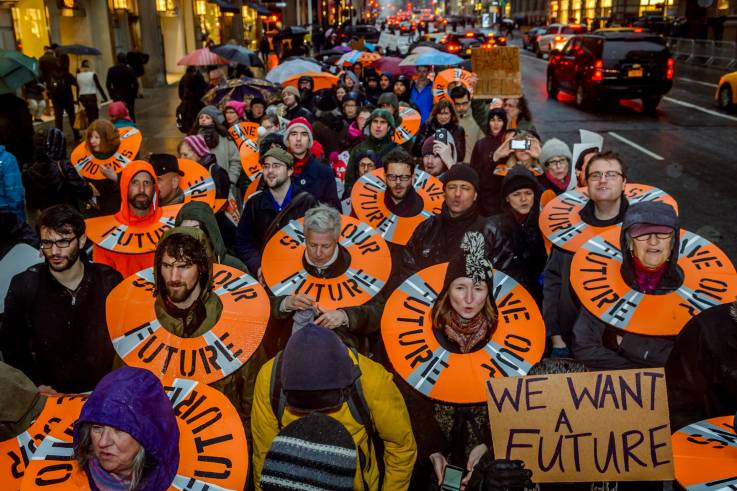 Ein Protestzug zieht durch eine Straße; die Demonstranten tragen stilisierte Rettungsringe mit der Aufschrift «SAVE OUR FUTURE» um den Hals.