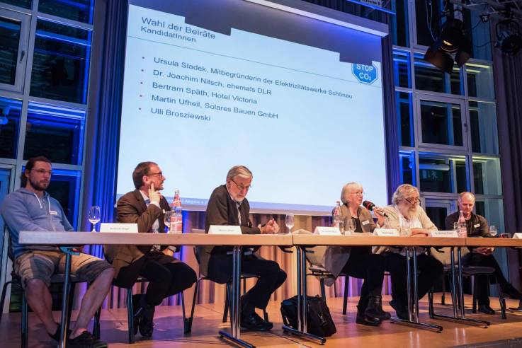 Auf dem Podium sitzt Ursula Sladek und erläutert einen Aspekt