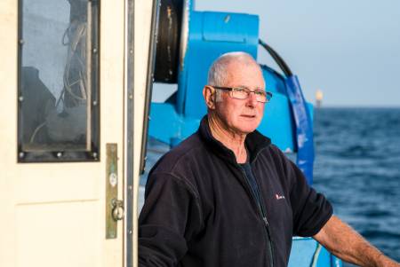 François Spinec steht an der Reling seines Fischerbootes und schaut in die Ferne.