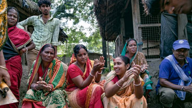 Indische Frauen  Männer sitzen und schauen in die Kamera.