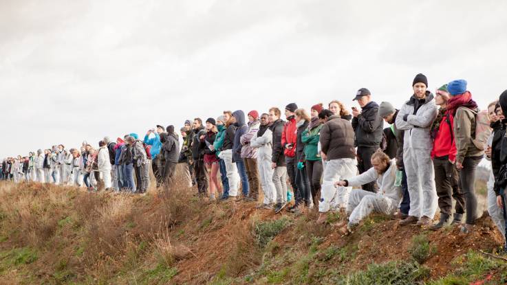 An der Geländekante stehen aufgereiht etwa vierzig bis fünfzig Demonstranten.