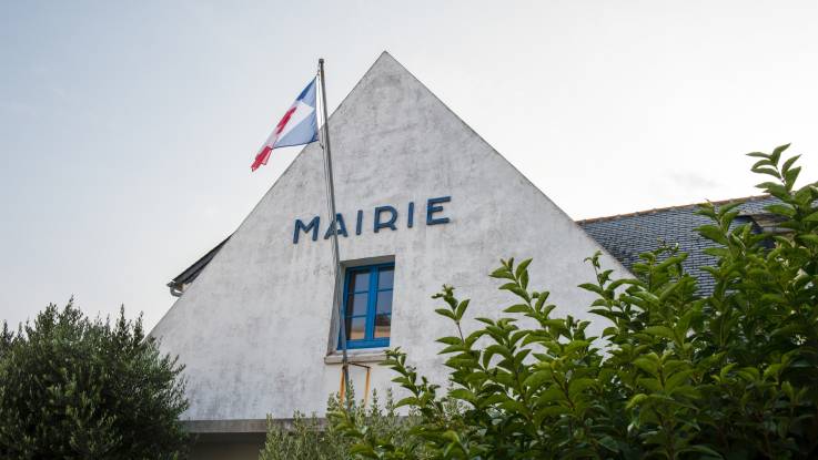 Auf dem Giebel des weißen Hauses steht in großen Lettern: Marie und die französische Fahren weht im Wind.