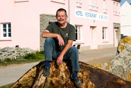 Der Chefkoch Patrick Hernandez sitzt auf einem Stein vor seinem Restaurant.