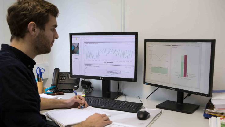 An zwei Computerbildschirmen wertet ein EWS-Mitarbeiter Energiedaten aus.