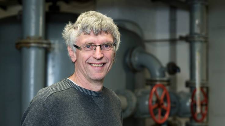 Ein freundlich in die Kamera blickender Mann mit grauen Haaren und Brille