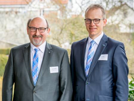 Die beiden Herren im Anzug schauen sehr freundlich in die Kamera.