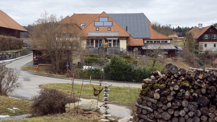 Ein großes Bauernhaus mit einer PV-Anlage auf dem Dach, im Winter aufgenommen