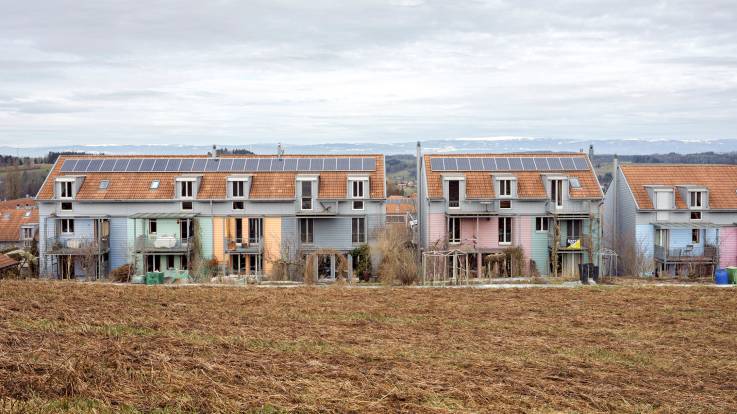 Häuserzeile mit PV-Anlagen, Hügelkette im Hintergrund