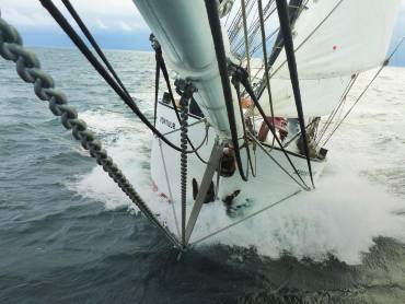 Mit voller Takelage durchpflügt ein Segelschiff das Meer.