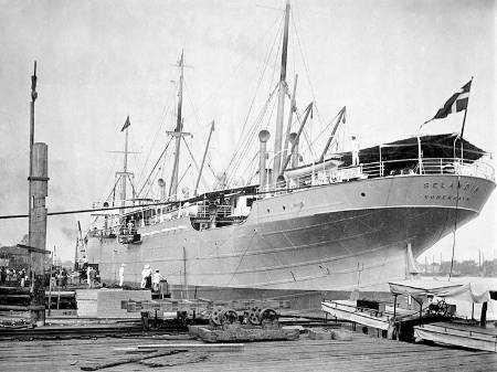 Historisches Foto, schwarzweiß: Ein Stahlschiff mit schlanken und eleganten Rumpf, hinter bugseitigen Aussparungen schwingen sich die befensterten Seitenwände zu einem geschlossenen Deck hoch; darüber zurückweichend weitere Decks sowie die Brücke.