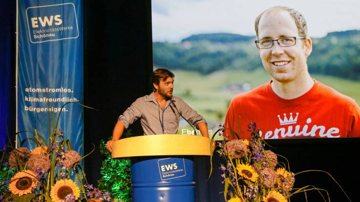 Alexander Sladek auf der Bühne im Hintergrund wird das Porträt von Syril Eberhard 