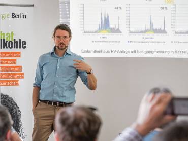 Ein junger Mann in hellblauem Hemd hält einen Vortrag zum Thema Solarenergie.