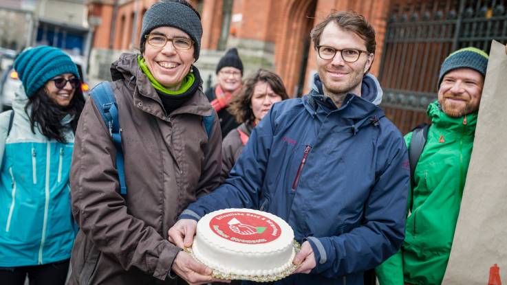 Eine Frau und ein junger Mann halten gemeinsam eine Torte.