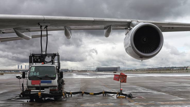 Unter dem Flügel eines Düsenflugzeuges steht ein Tankwagen neben der Turbine; das Flugzeug wird betankt.