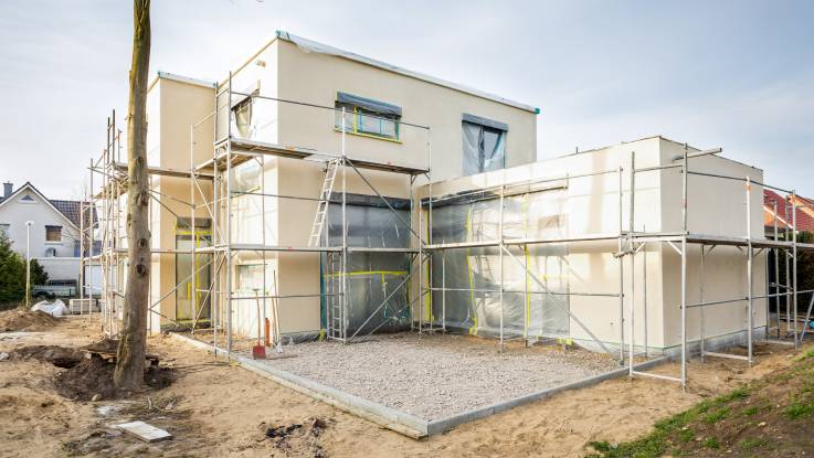 Ein Mehrfamilienhaus im Bau, die Baugerüste stehen noch.