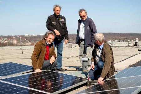 Vier Menschen im Gespräch, vor ihnen PV-Module