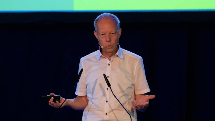 Thomas Jorberg referiert mit Fernbedienung in der Hand