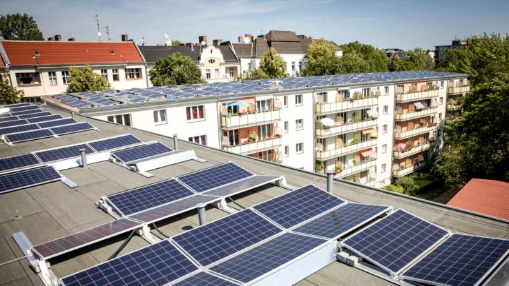 Blick über ein Flachdach, auf dem viele PV-Module installiert sind.