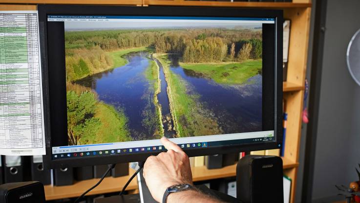 Ein Computermonitor in einem Büro mit einem Foto von einem Feuchtgebiet.