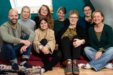 Gruppenfoto von acht auf dem  Boden sitzenden jungen Menschen.