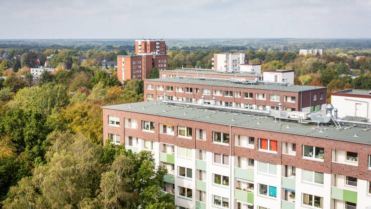 Blick auf eine im Grünen gelegenen Wohnsiedlung, auf dem Dach eines der Wohnblöcke sind Abluftanlagen zu erkennen.