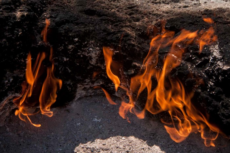 Orangefarbene Flammen schlagen aus einer Erdritze.