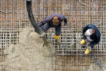 Frischer Beton wird auf Stahlmatten gegossen.