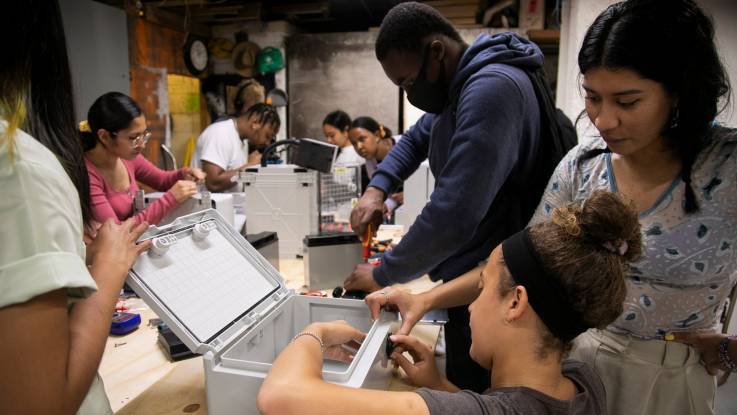 A lively workshop situation with eight young people working on various electrical installations.