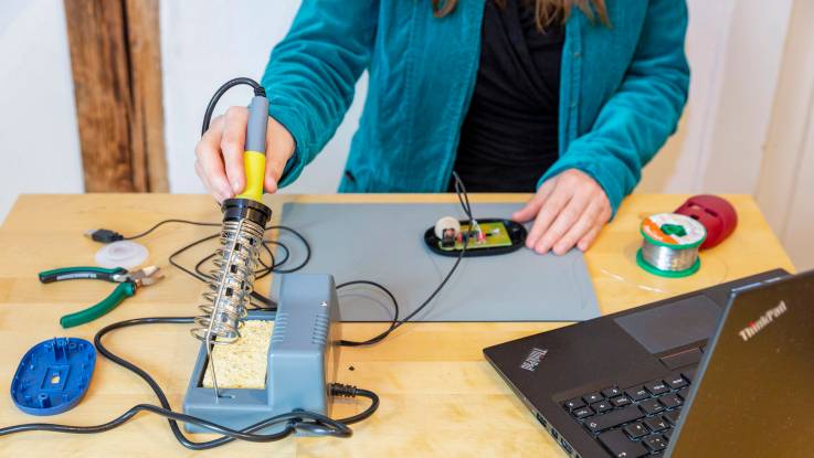 Der Arbeitsplatz für das Zusammenlöten der fairen Computermaus. Zu sehen sind die Hände von Lena Becker.