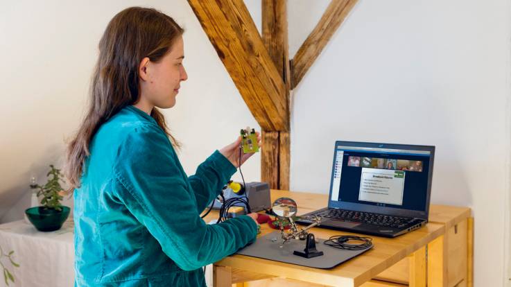 Lena Becker zeigt über ihrer Laptopkamera den Teilnehmenden die Bauteile .