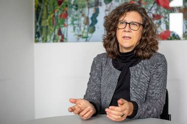 Frau mit beeindruckenden Locken, lebendig gestikulierend im Gespräch.