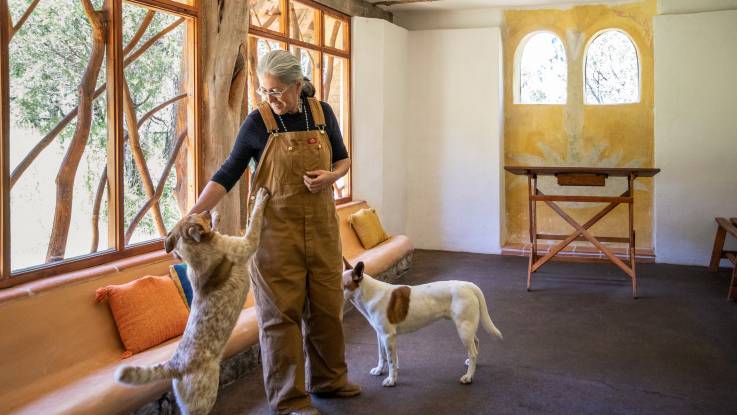 In einem hellen großen Raum steht die Architektin, flankiert von ihren beiden Hunden.